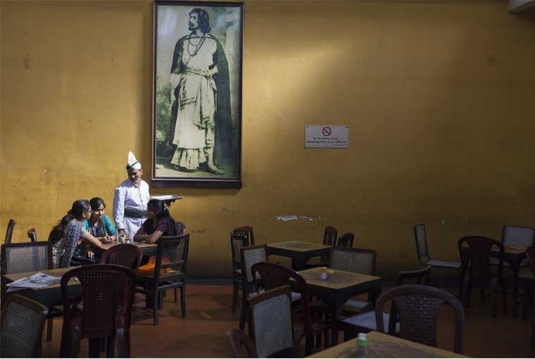 The Palaces of Memory Â©Stuart Freedman, A waiter serves schoolgirls beneath a portrait of Rabindranath Tagore in the Indian Coffee House, Kolkata, 2013, C-type print Courtesy Tasveer
